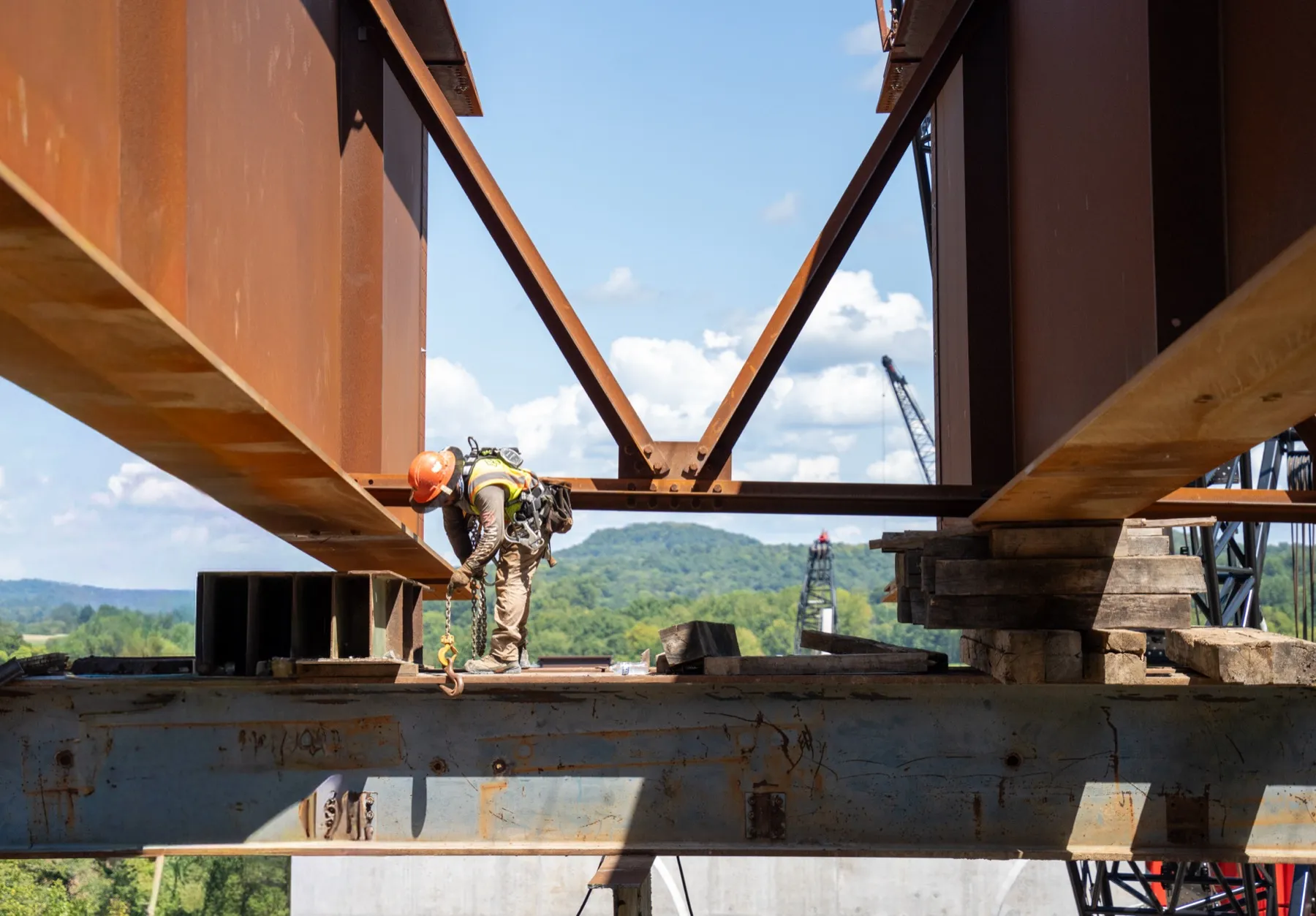 Ironworker standing between steel bridge girders against a blue sky